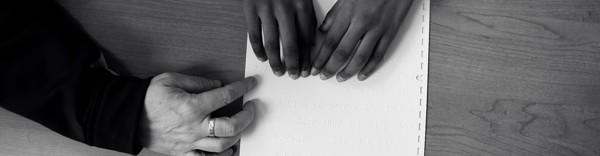 Student receives help reading a braille document